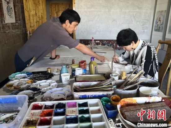 圖為2020年8月下旬，敦煌“80后”畫家張杰龍(左)在為云南麗江“學(xué)生”莫北講解敦煌壁畫的繪畫技巧?！●T志軍 攝