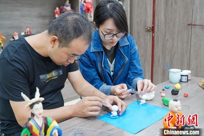 <a target='_blank'  data-cke-saved- >中新社</a>記者(右)現(xiàn)場體驗面塑制作過程?！￡悹帍?攝