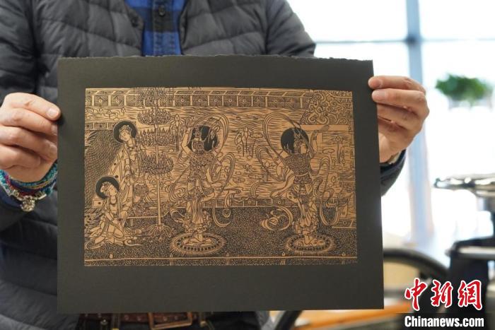 圖為手工書藝人展示敦煌雕版壁畫印刷品。　九美旦增 　攝