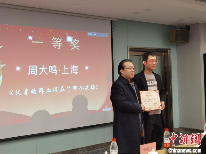 圖為作家、西北師范大學(xué)新聞與傳媒學(xué)院院長徐兆壽頒發(fā)一等獎證書，代領(lǐng)獎?wù)呱吓_領(lǐng)獎。　楊娜 攝