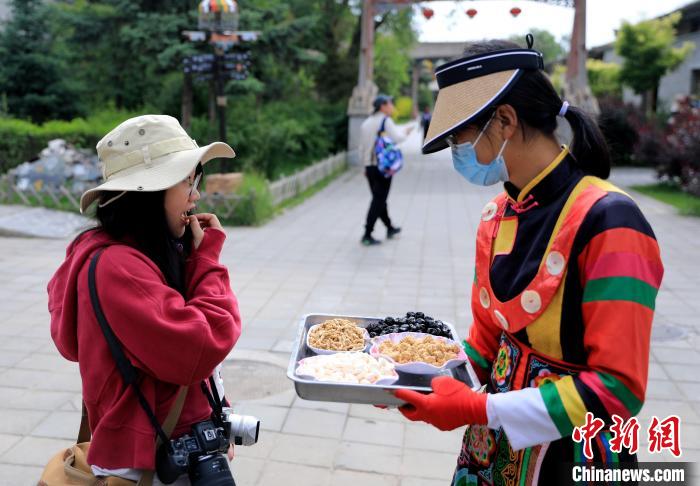 圖為身穿土族服飾的女性介紹當地特色小吃?！⊙Φ?攝