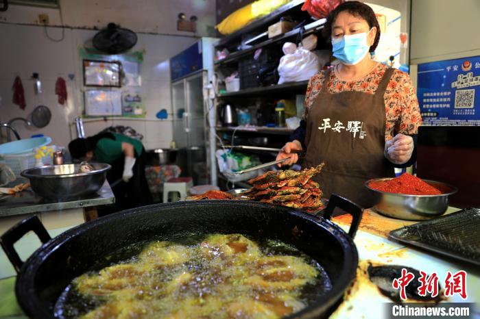 圖為平安驛·河湟民俗文化體驗地內(nèi)的商戶炸干板魚?！⊙Φ?攝