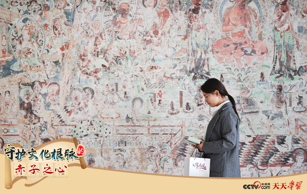2023年4月25日，敦煌研究院文物數(shù)字化保護團隊創(chuàng)意營銷人員廖雪婷從一幅高保真復(fù)制壁畫前走過。