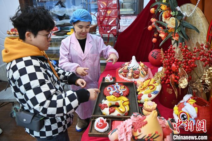 1月25日，隨著春節(jié)臨近，蘭州一花饃店“龍”元素花饃熱銷。圖為工作人員向顧客推薦“龍”元素花饃。九美旦增 攝</p><p>