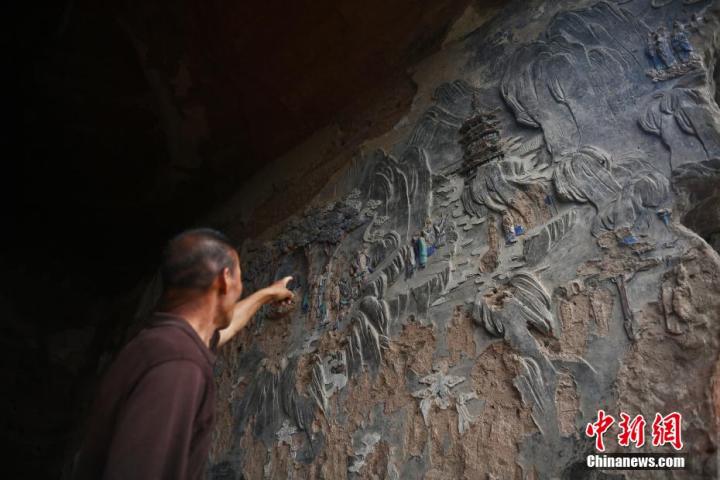 7月15日，甘肅省平?jīng)鍪袥艽h百里石窟長廊羅漢洞石窟內(nèi)，該窟文保員郭建平介紹窟內(nèi)石刻彩繪壁畫。郭建平家中三代人曾自發(fā)保護羅漢洞石窟。羅漢洞石窟遺存40余個窟龕，以北魏至清代風格為主。中新社記者 李亞龍 攝