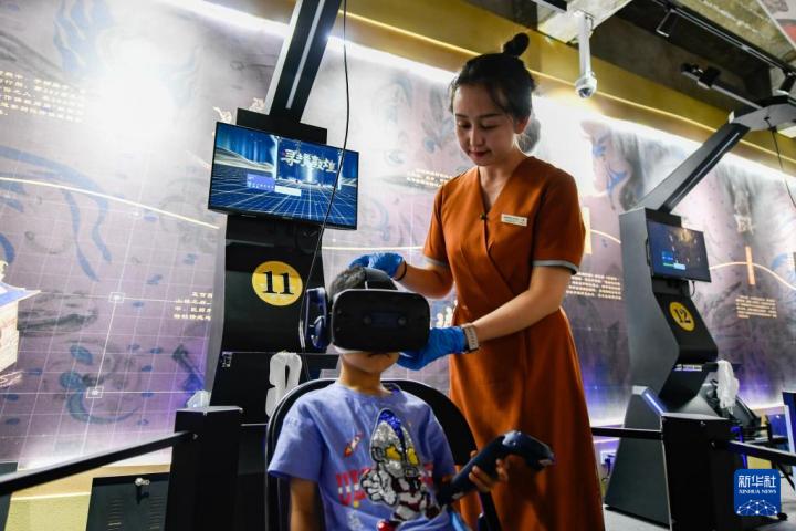 7月22日，敦煌研究院文化弘揚部工作人員引導游客佩戴使用VR設備。新華社記者 郎兵兵 攝</p>
<p>