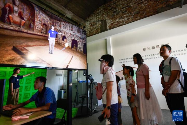 7月22日，游客體驗“尋境敦煌——數(shù)字敦煌沉浸展”后，在虛擬演播廳拍攝一段真人與洞窟虛擬場景交互的視頻。新華社記者 郎兵兵 攝</p>
<p>