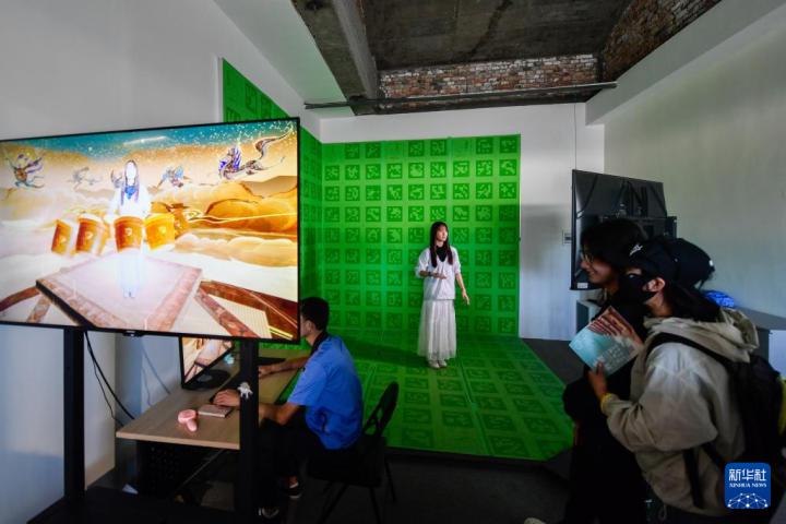 7月22日，游客體驗“尋境敦煌——數(shù)字敦煌沉浸展”后，在虛擬演播廳拍攝一段真人與洞窟虛擬場景交互的視頻。新華社記者 郎兵兵 攝</p>
<p>